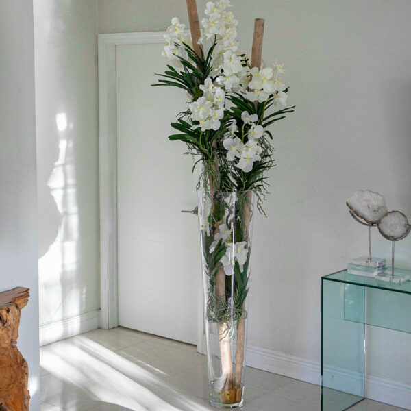 Weiße Vanda-Orchideen und Treibholz in einem großen, konischen Glaszylinder