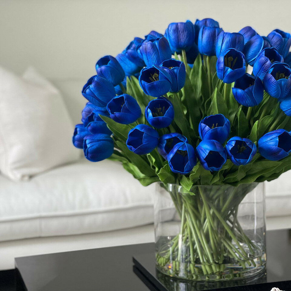 Blaue Tulpenarrangements in großer zylindrischer Vase